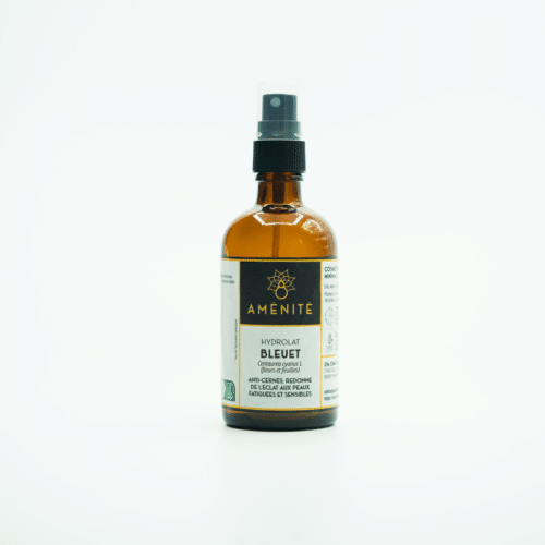 Flacon en verre ambré de 100ml avec pompe spray noire contenant de l'hydrolat de Bleuet de la marque Aménité, posé sur un fond blanc épuré.
